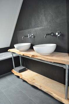 two white bowls sit on top of a wooden shelf in a bathroom with black walls