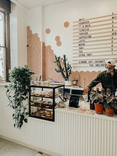 a man standing behind a counter filled with pastries and desserts in front of a window