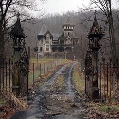 an old abandoned house is seen through the gated entrance to a dirt road in front of it