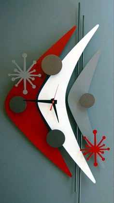 a red and white clock on the side of a building with snowflakes hanging from it's sides