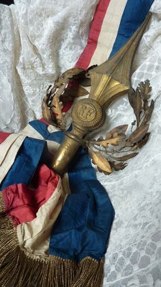 an ornate gold mask with red, white and blue ribbons around it