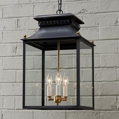 an outdoor hanging lantern with three candles on the bottom and one light in the middle