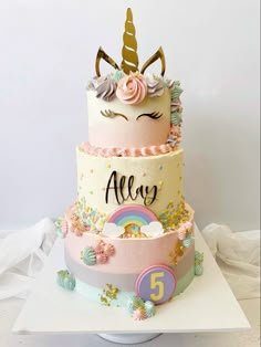 a three tiered cake decorated with unicorns and rainbows on the top layer