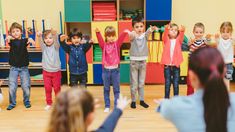 a group of children standing around each other in front of a classroom full of people