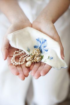 a woman in white dress holding a purse with pearls and brooches on it