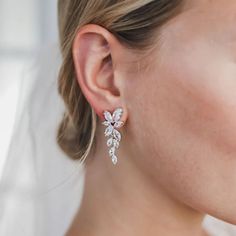 a close up of a woman wearing earrings with flowers on it's ear and the back of her head