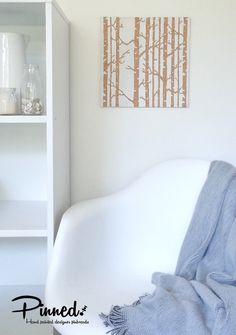 a white chair with a blanket on top of it in front of a book shelf