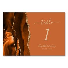 an orange and gold wedding table card with the number one on it's side