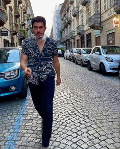 a man walking down the street in front of parked cars