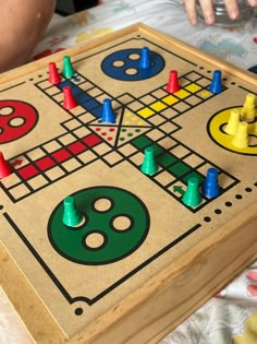 a wooden board game set up on top of a bed next to a child's hand