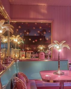 a room with pink walls and tables, chairs and lights in the window sill