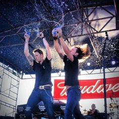 two men are performing on stage with their hands in the air