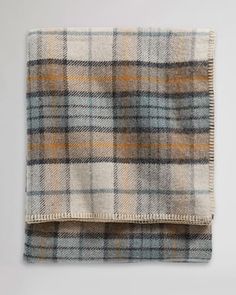 a plaid blanket folded on top of a white wall with grey and yellow colors in the background