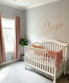 a baby's room with a crib and pink drapes on the windowsill