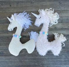 two white stuffed unicorns sitting on top of a wooden floor