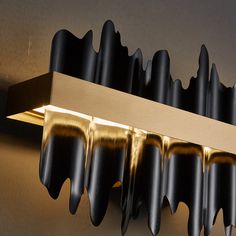 a light that is on the side of a wall with some black and gold paint