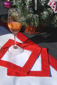 a glass of wine sitting on top of a red and white placemat next to a christmas tree