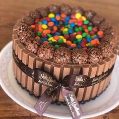 a chocolate cake decorated with candy and candies on a white plate next to a wooden table