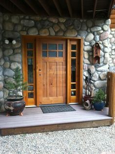 a wooden door sitting on the side of a stone wall next to a planter