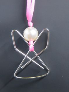 an ornament with a pearl in the center on a pink ribbon and silver wire