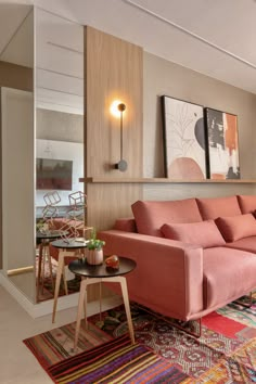 a living room with pink couches and colorful rugs on the floor in front of it