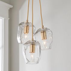 three clear glass lights hanging from a ceiling fixture in a room with white walls and windows