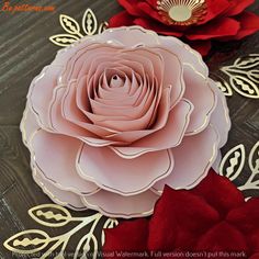 two paper flowers sitting on top of a table next to each other with gold trimmings