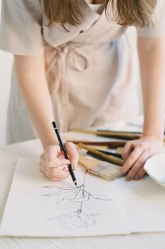 a woman holding a brush and drawing on paper