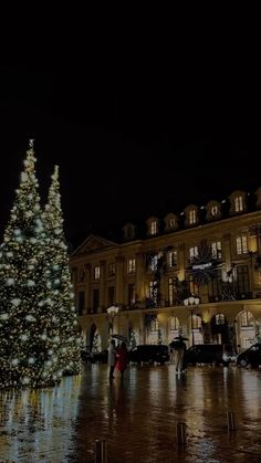 a large christmas tree is lit up in front of a building with lights on it