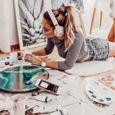 a woman is laying on the floor with her headphones over her eyes and painting