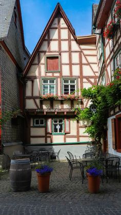 an old half - timbered house with potted plants and chairs in the courtyard