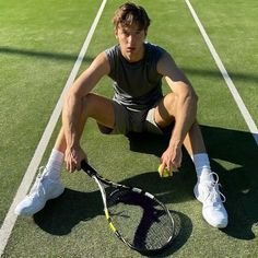 a man sitting on the ground with a tennis racket and ball in his hand