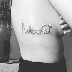 a black and white photo of a woman's stomach with the skyline tattoo on it