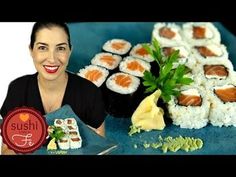 a woman holding a plate with sushi on it next to some other food items