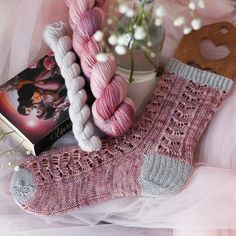 a pink sock and some yarn next to a book