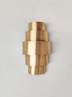 a wall mounted light on the side of a white wall with gold colored metal fittings