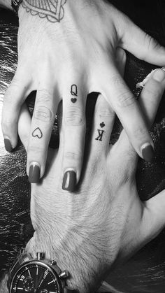 two people holding hands with tattoos on their fingers