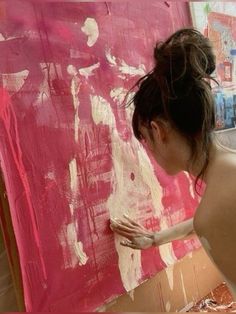 a woman is painting with pink and white paint