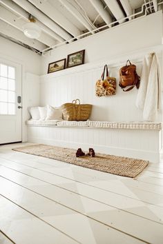 a room with white walls and wooden flooring, two purses hanging on the wall