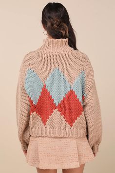 a woman is wearing a sweater with an argyle pattern on the back, and has her hands in her pockets