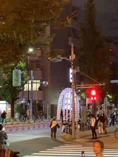 people are sitting on benches at the crosswalk in front of a red traffic light