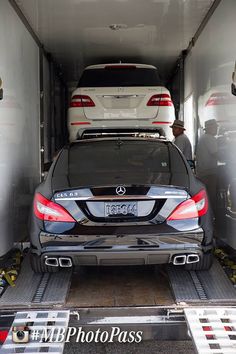 two mercedes benzs are parked in the back of a car carrier with their doors open