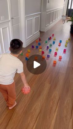 a little boy standing on top of a wooden floor with lots of blocks in front of him