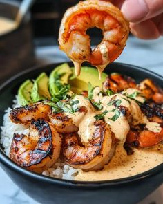 someone is dipping shrimp into a bowl of rice