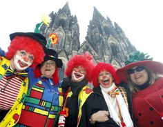 four people dressed in clown costumes posing for a photo with the cologne cathedral in the background