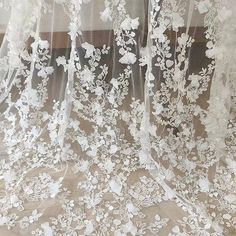 white lace with flowers and leaves on a sheer fabric background, close - up photo