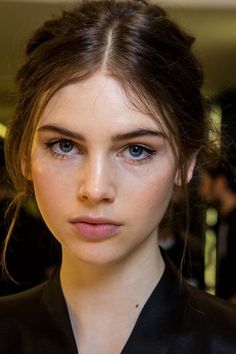 a close up of a person wearing a black shirt and hair in a pony tail