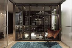 a chair sitting on top of a blue rug next to a glass case filled with books