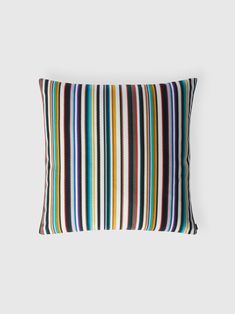 a multicolored striped pillow sitting on top of a white wall