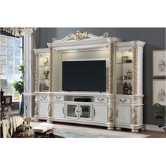 a large white entertainment center with gold trimmings and ornate carvings on the doors